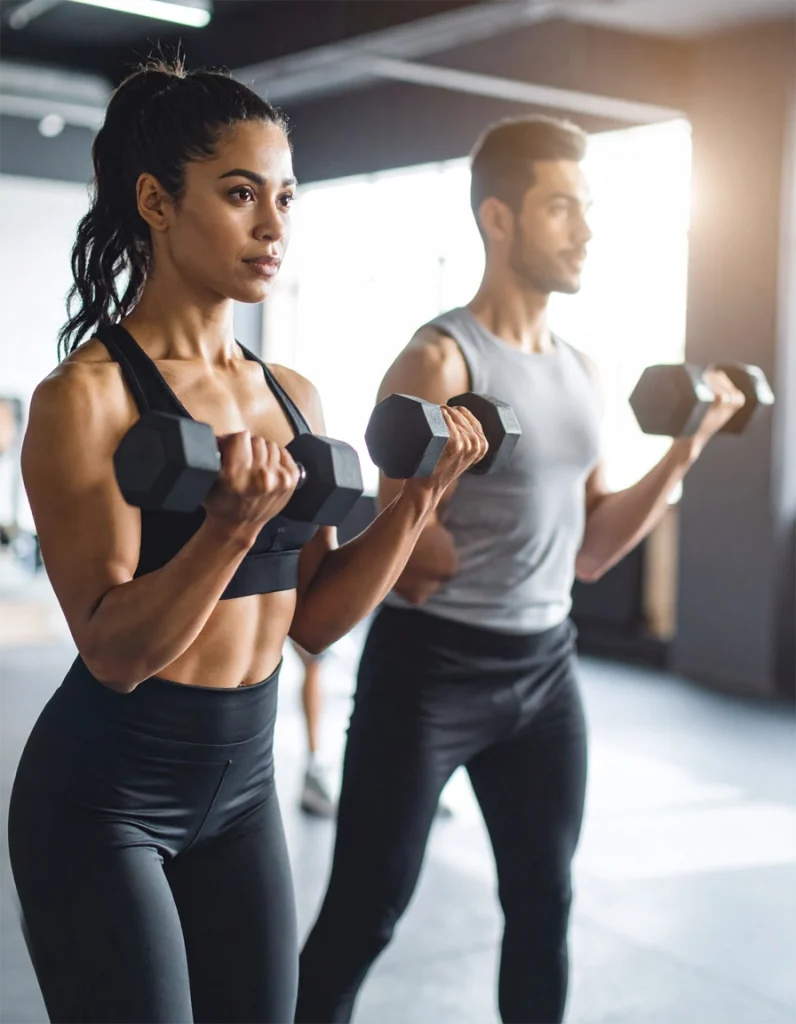Pessoas treinando com alteres em academia de musculação